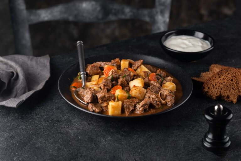 Cubos de carne guisados com batatas em um prato preto